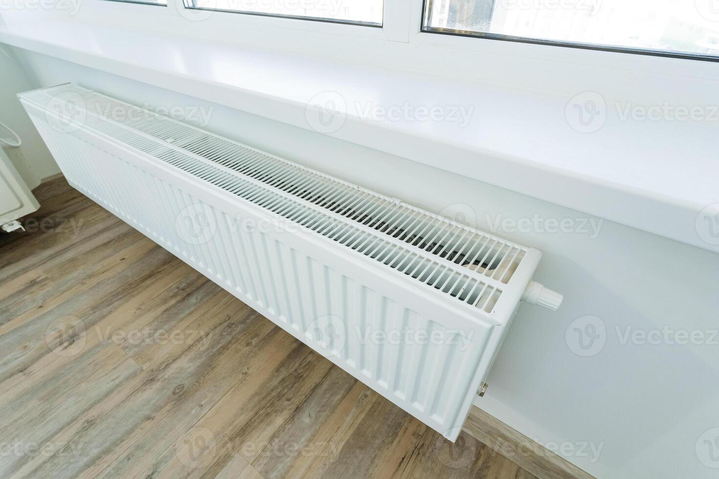 A white radiator on the window sill adds warmth and comfort to the room, enhancing the appeal of hardwood and laminate flooring and creating a cozy atmosphere for all who enter photo
