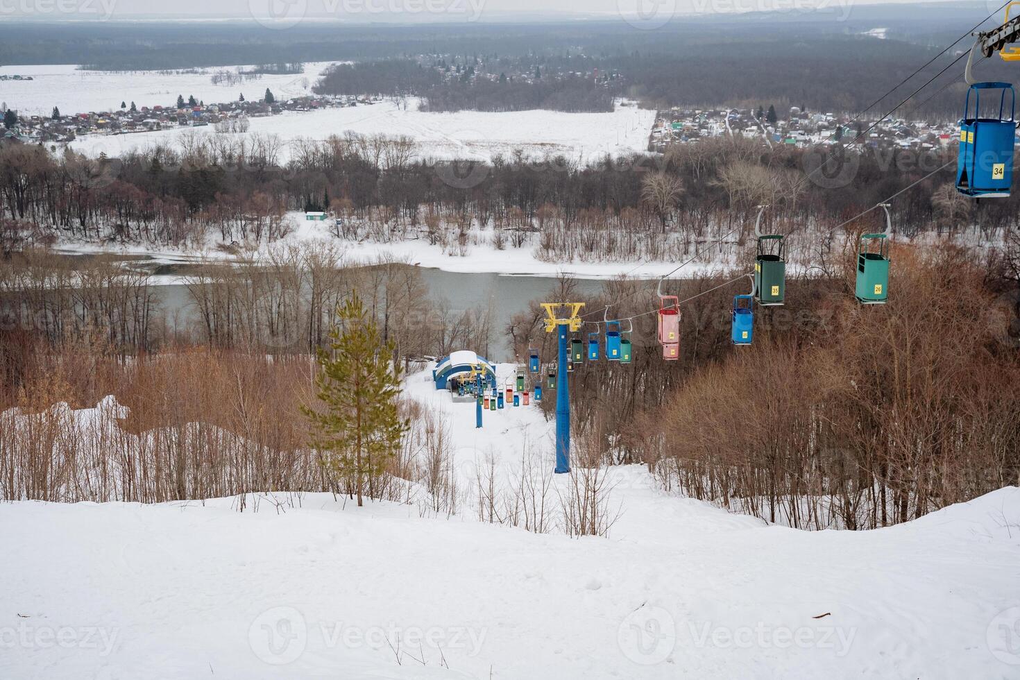A charming chairlift in a winter landscape overlooks serene slopes and a calm river, creating an idyllic setting for fun activities and thrilling adventures with loved ones photo
