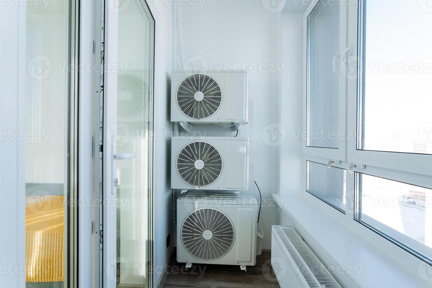 On a spacious balcony, there are two air conditioners that are neatly stacked one directly on top of the other. They prominently enhance the utility and overall functionality of the space photo