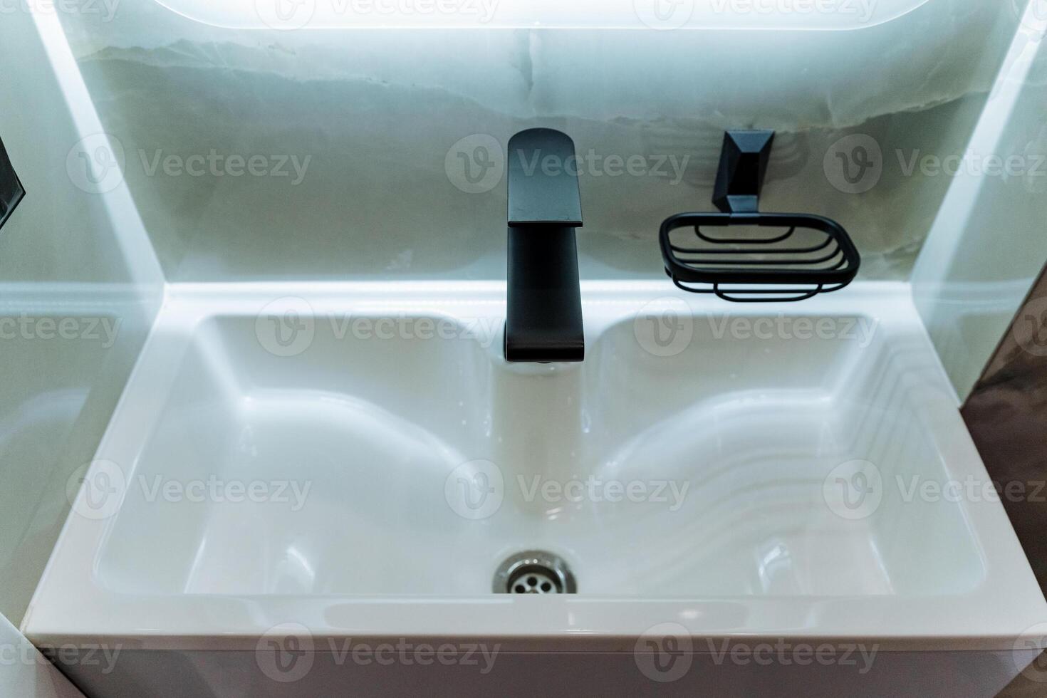The elegantly designed bathroom boasts a contemporary sink accompanied by a chic black faucet and a coordinating soap dish, all combining to establish a sophisticated, modern aesthetic photo