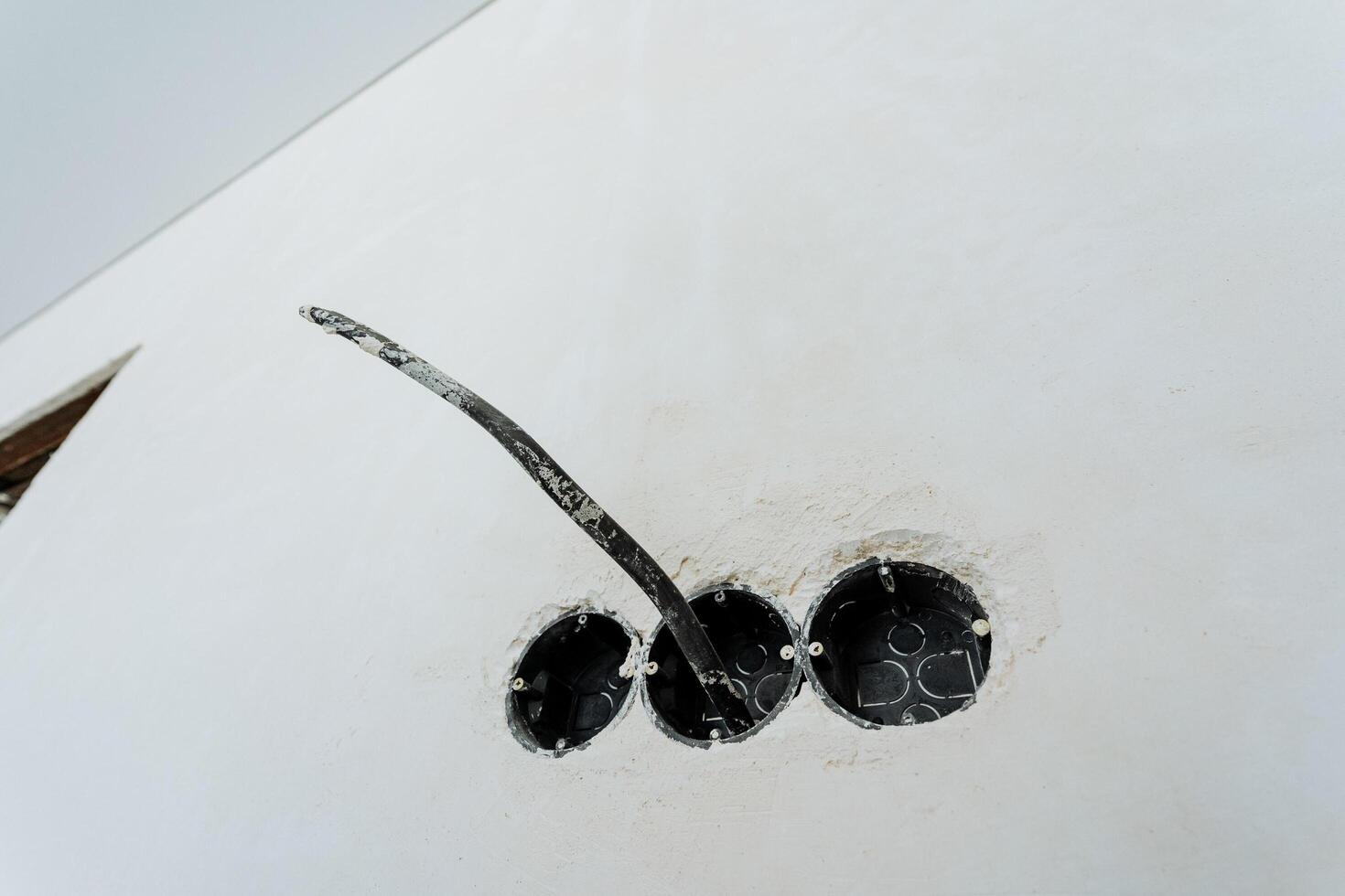 This image features a closeup view of three electrical outlets positioned on a plain white wall, showcasing the details of the outlets and the walls texture for better visual appreciation photo