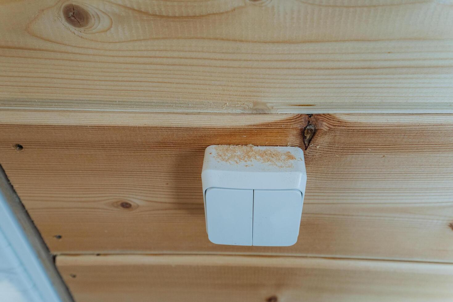 A bright white light switch is hanging down from the ceiling of a beautifully crafted wooden wall, adding a modern touch to the natural aesthetic of the rooms interior design photo