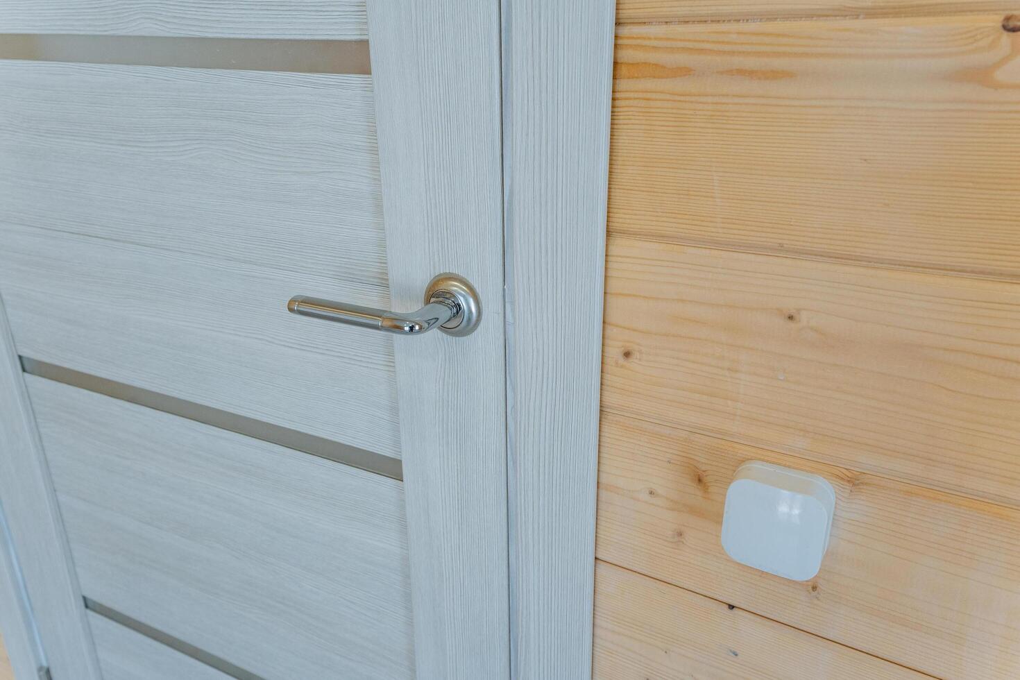 A beautifully crafted white door with a sturdy metal handle stands against a textured wooden wall, creating a captivating contrast and enhancing the homes aesthetic appeal photo
