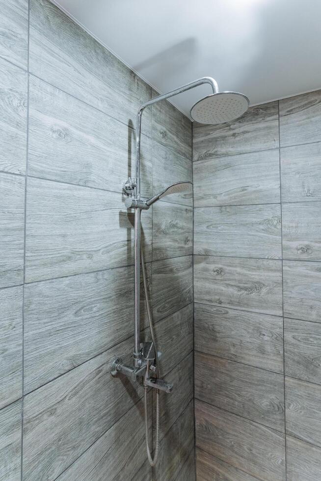 A shower head is elegantly hanging from the ceiling in a stylishly designed bathroom, which enhances the overall aesthetic of the space and offers a refreshing shower experience photo