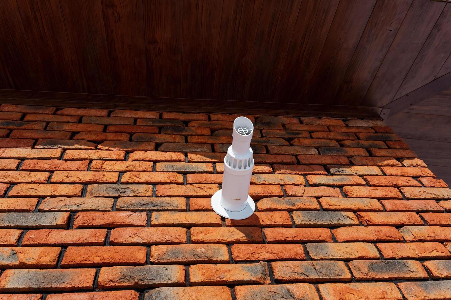 A white pipe is placed on top of a sturdy brick wall, which is composed of assorted bricks and mortar forming the structure, showcasing the craftsmanship in building materials used photo