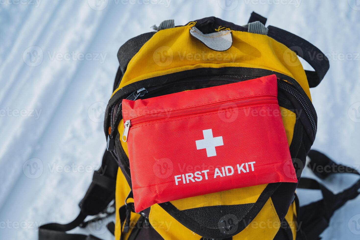 A bright yellow backpack featuring a prominently placed red first aid kit attached to it, making it easily visible and prepared for any emergency situations that might arise photo
