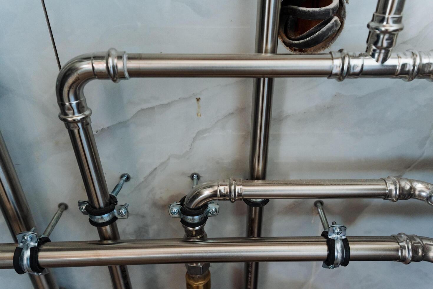 This captivating image features a closeup of polished stainless steel pipes in a modern bathroom, highlighting their sleek, shiny finish that reflects light beautifully photo