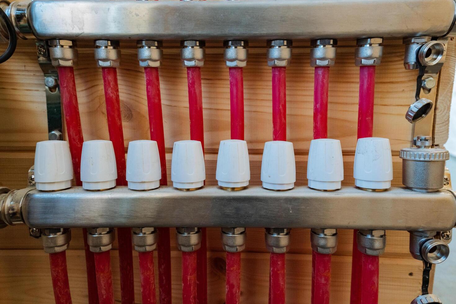 In this image, we can see a closeup view of a heating system that features distinct red pipes along with white caps, showcasing the intricate design and components involved photo