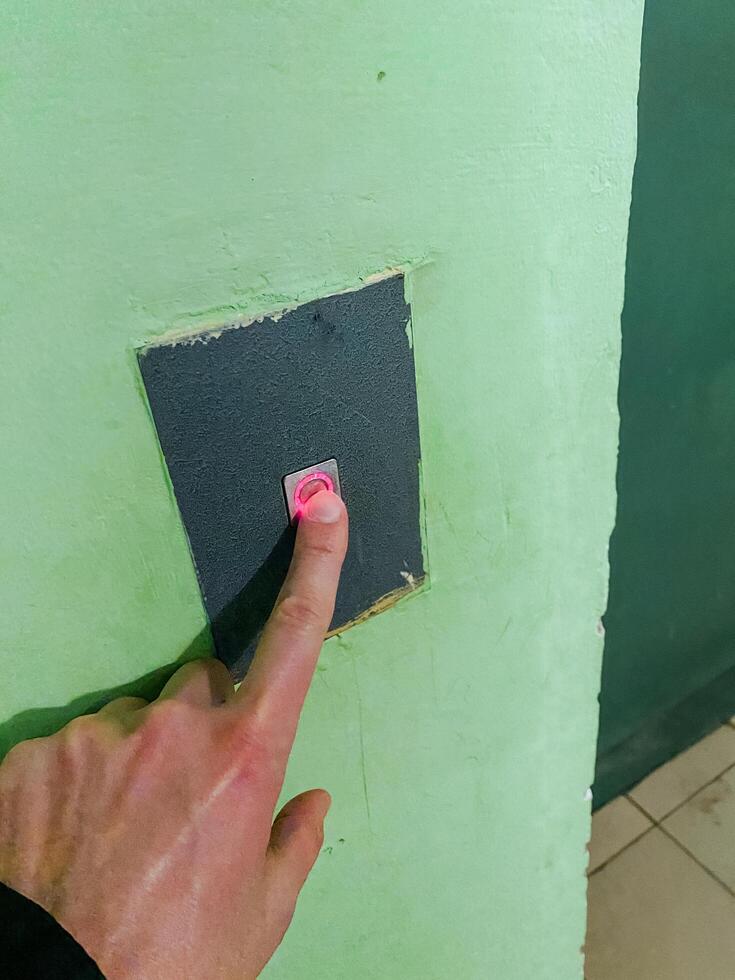 An enthusiastic individual is energetically pressing a shiny button that is affixed to a bright green wall, creating an intriguing and captivating scene that draws in curious onlookers photo