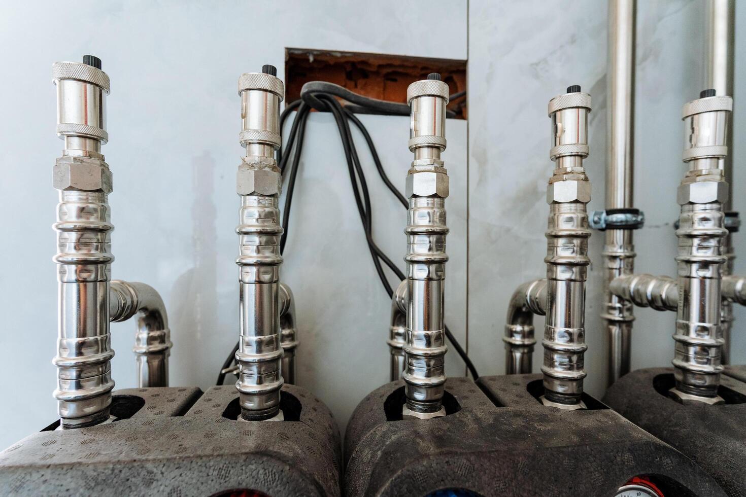 Shiny, polished stainless steel pipes are securely fixed to a sturdy wall, highlighting their robust design, versatility, and vital role in plumbing and engineering applications photo