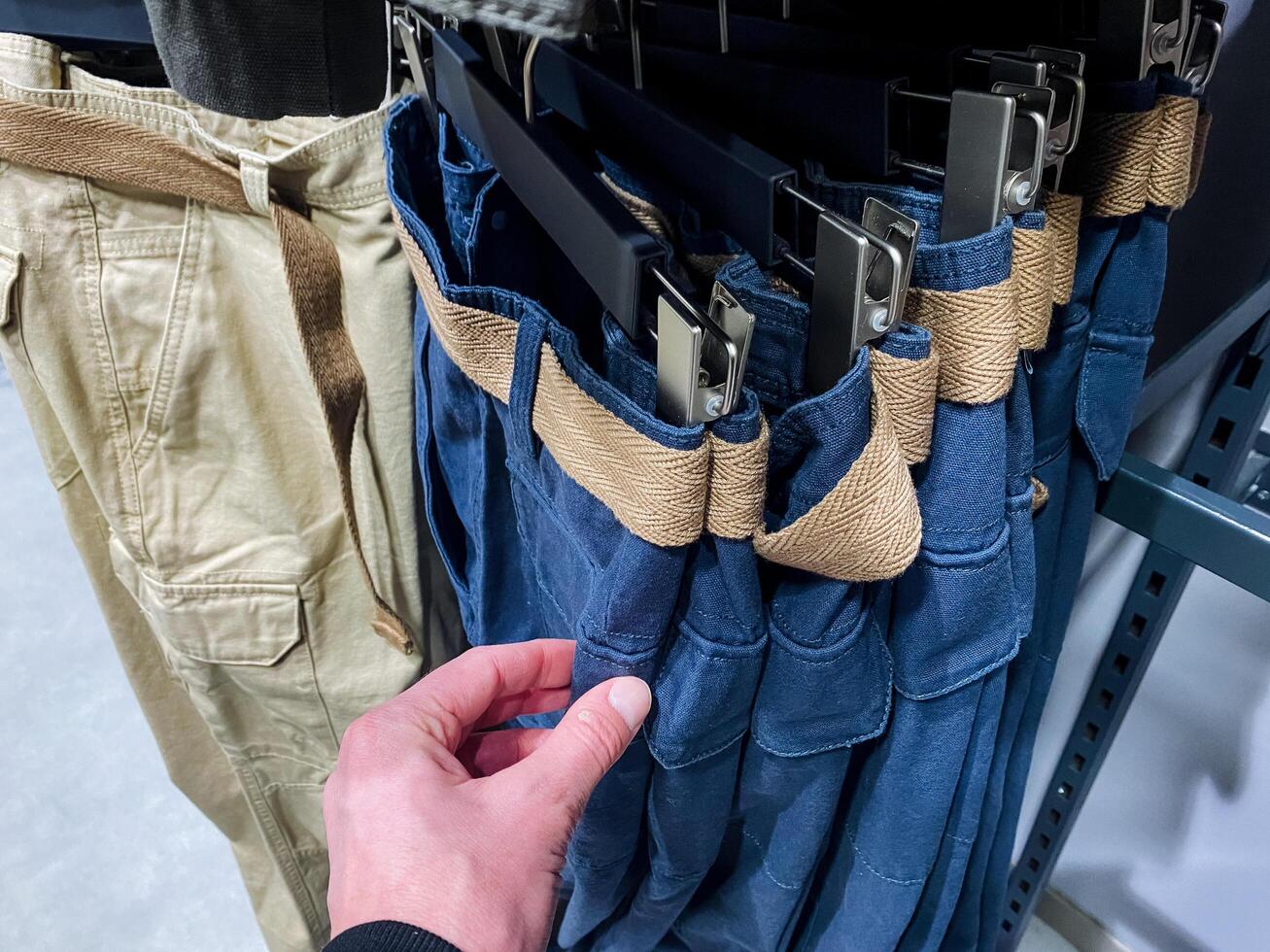 A person is carefully reaching into a pocket of a stylish and comfortable pair of denim pants, perhaps looking for something they need or have misplaced within the pocket photo