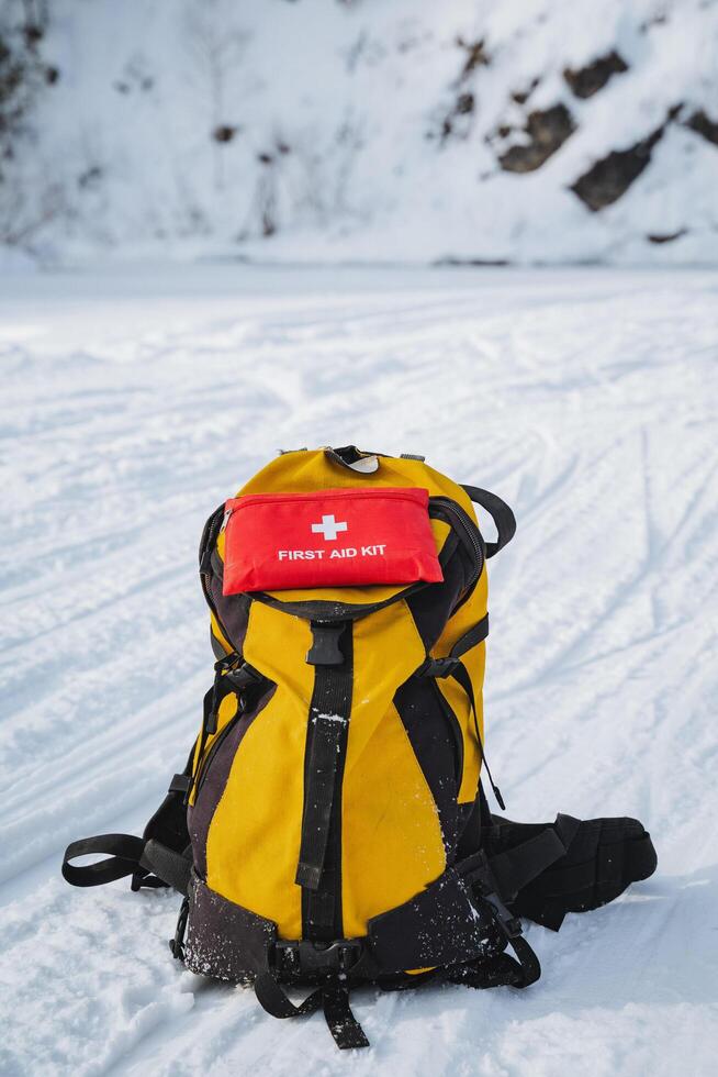 A yellow backpack with a red first aid kit on top of it photo