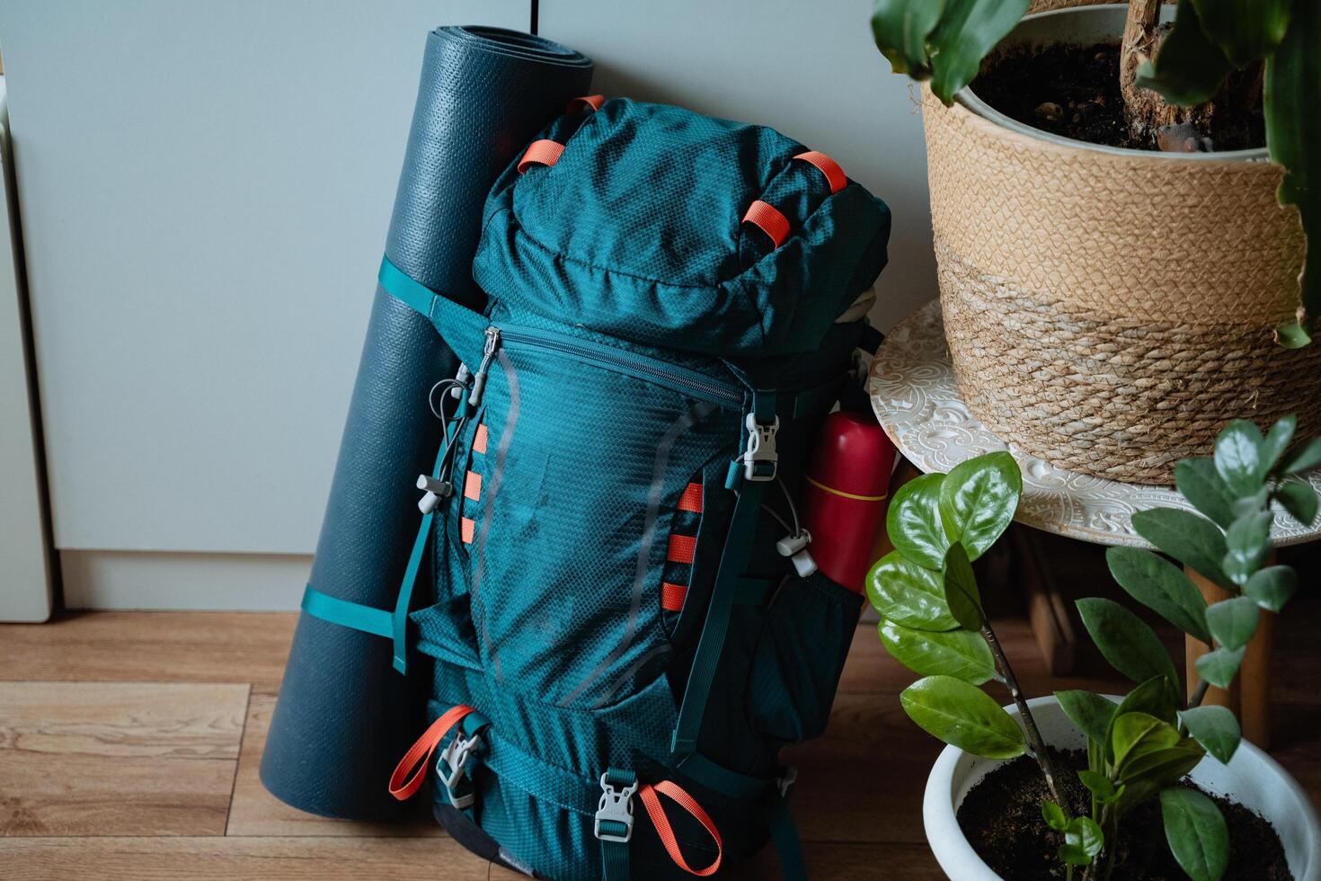 A bright blue backpack is casually resting on the polished wooden floor, positioned close to a neatly rolled yoga mat, which together creates a serene and peaceful atmosphere in the room photo
