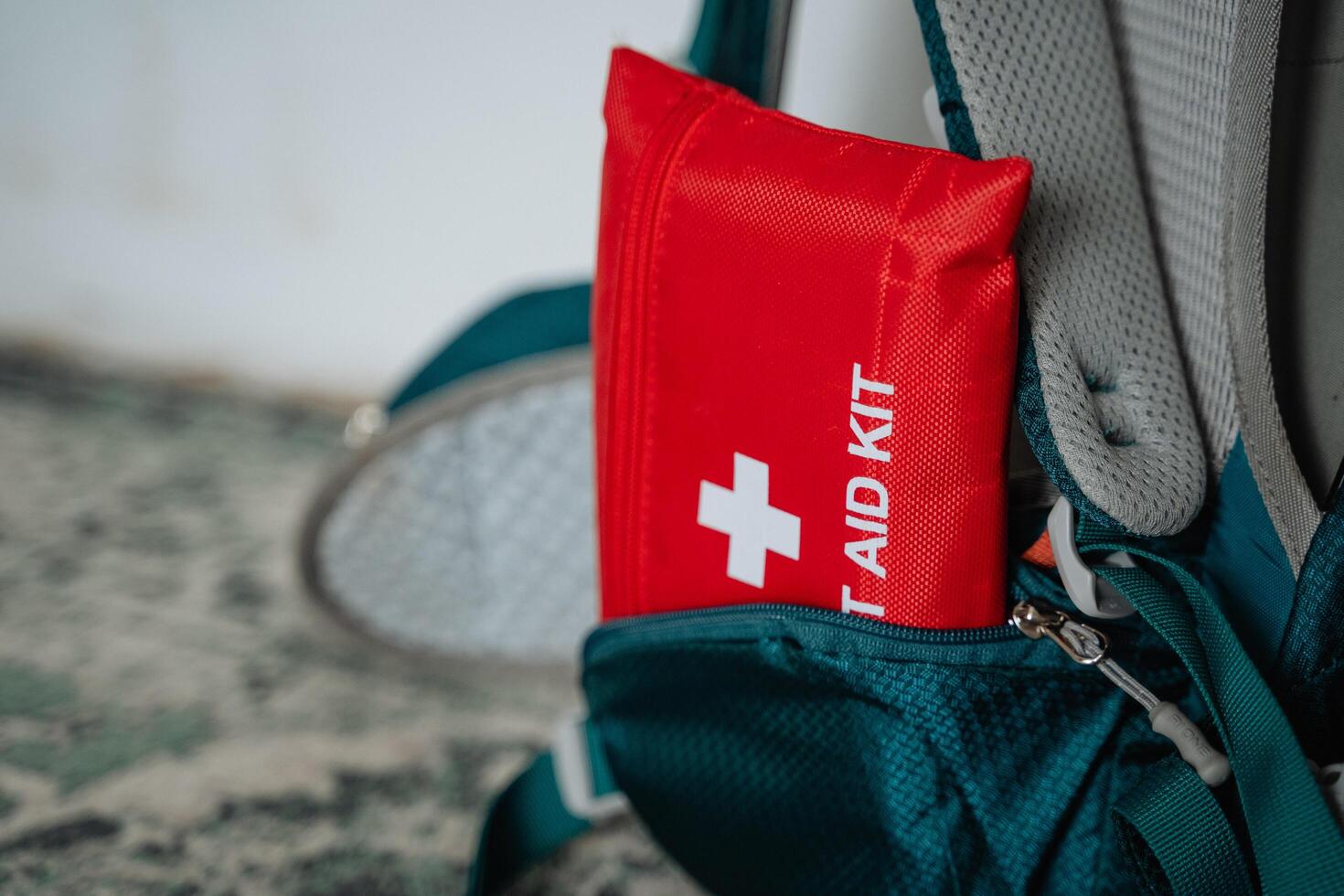 A bright red first aid kit is protruding from a backpack, making it easily visible and accessible in case of emergencies while on the go, ensuring safety during outdoor activities photo