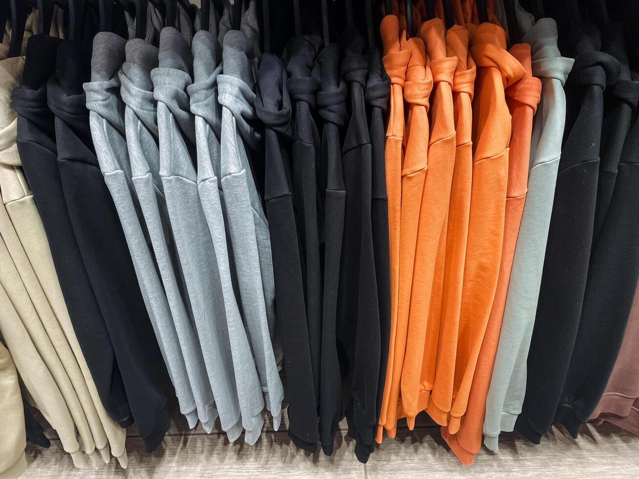 A bunch of various colored shirts are currently hanging neatly on a clothing rack for display, showcasing an array of vibrant hues and styles for potential buyers to admire photo