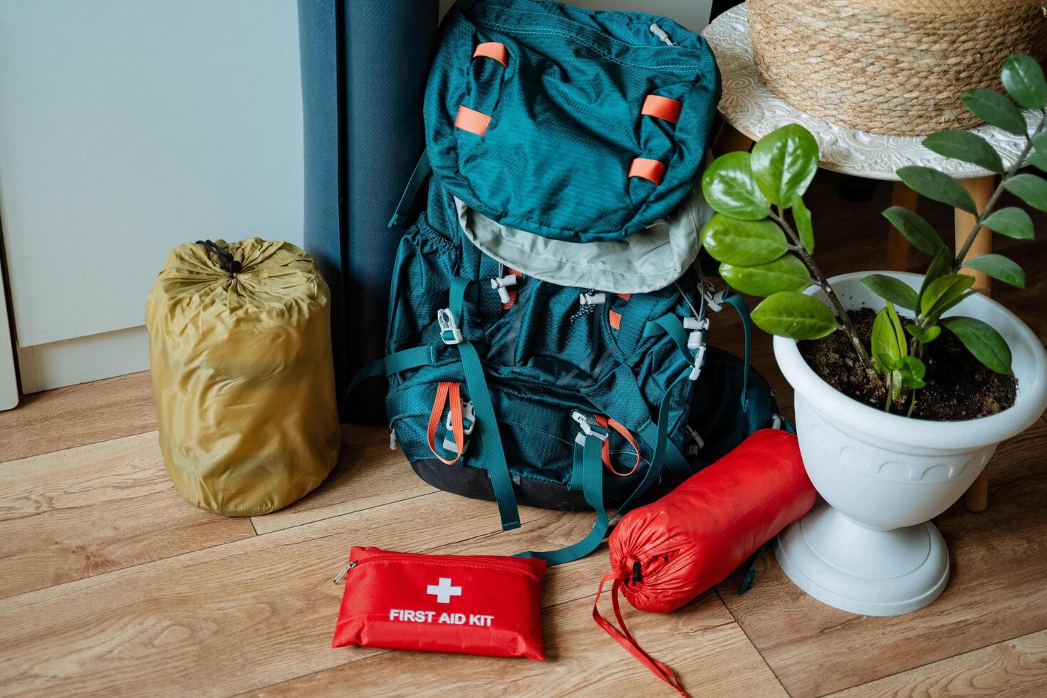 A backpack is sitting on a wooden floor next to a first aid kit photo