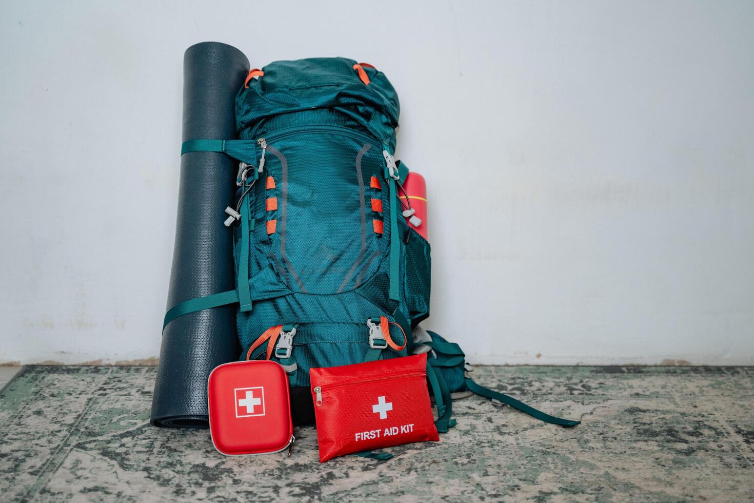 A vibrant green backpack that contains a bright red first aid kit along with a comfortable yoga mat, perfect for outdoor activities and keeping yourself prepared and healthy photo
