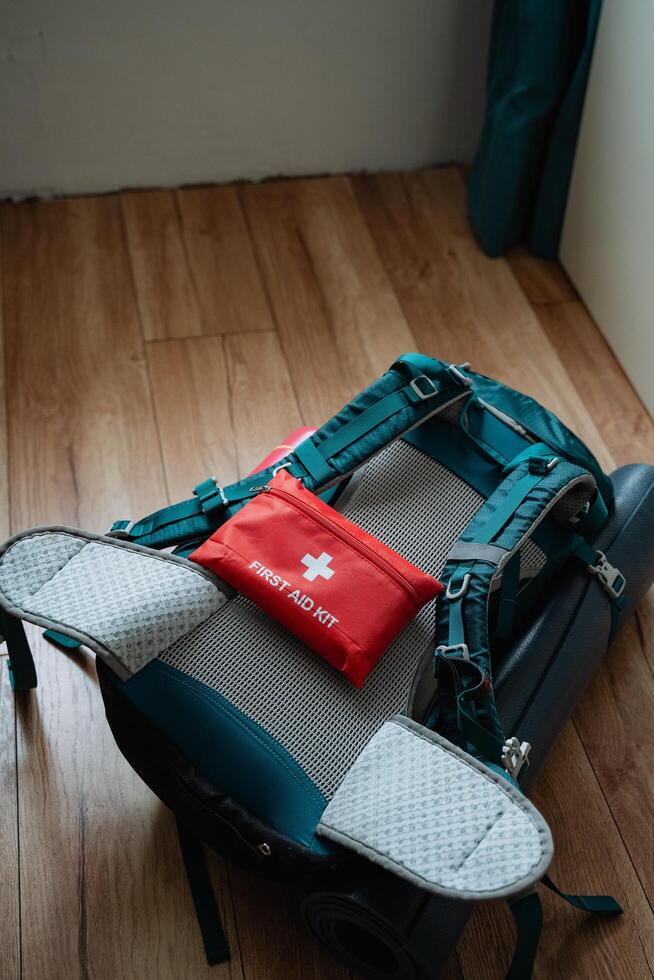 A bright red first aid kit is prominently and visibly situated on a sturdy backpack, fully prepared for any potential emergencies that may occur during your travels or outdoor adventures photo