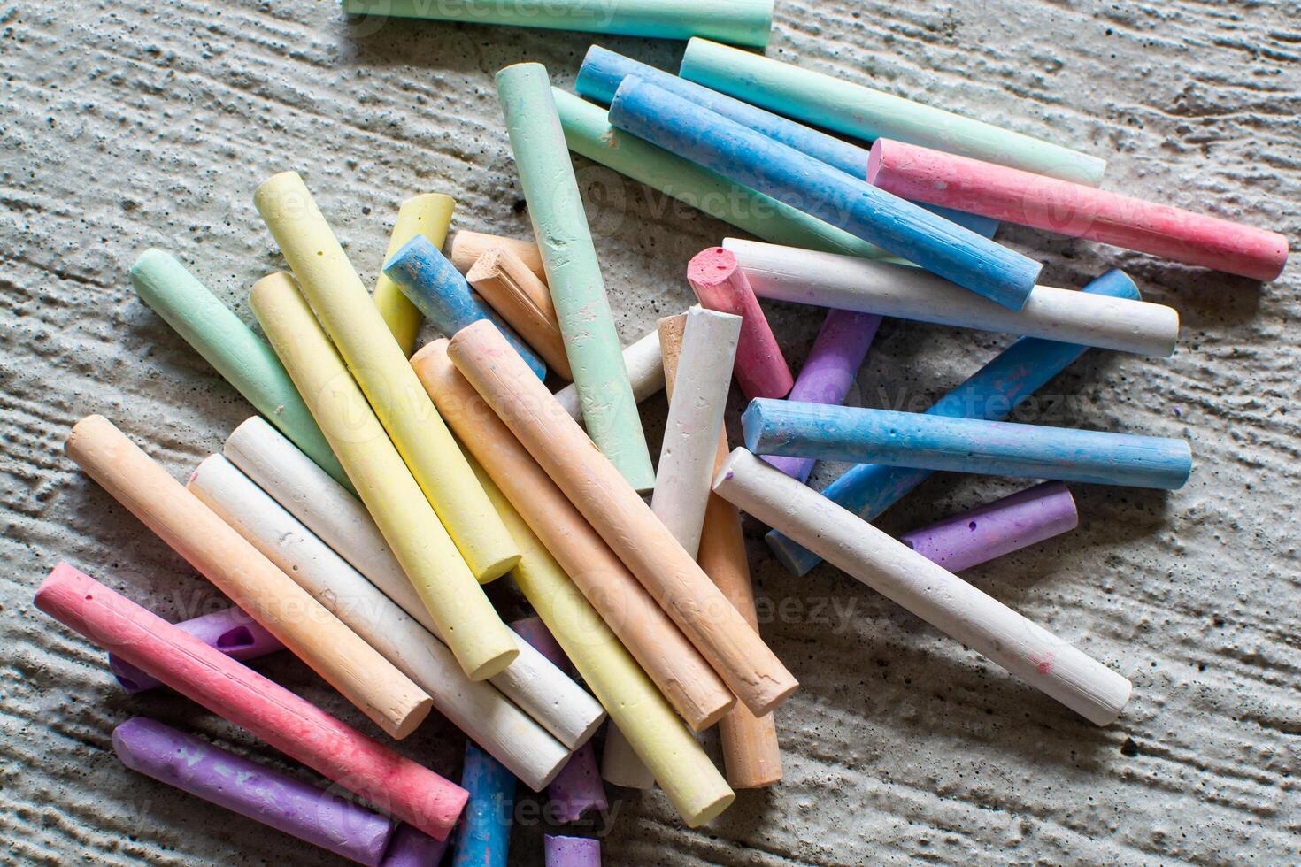 View of a set of multi-colored crayons for drawing for children's creativity on the concrete floor photo