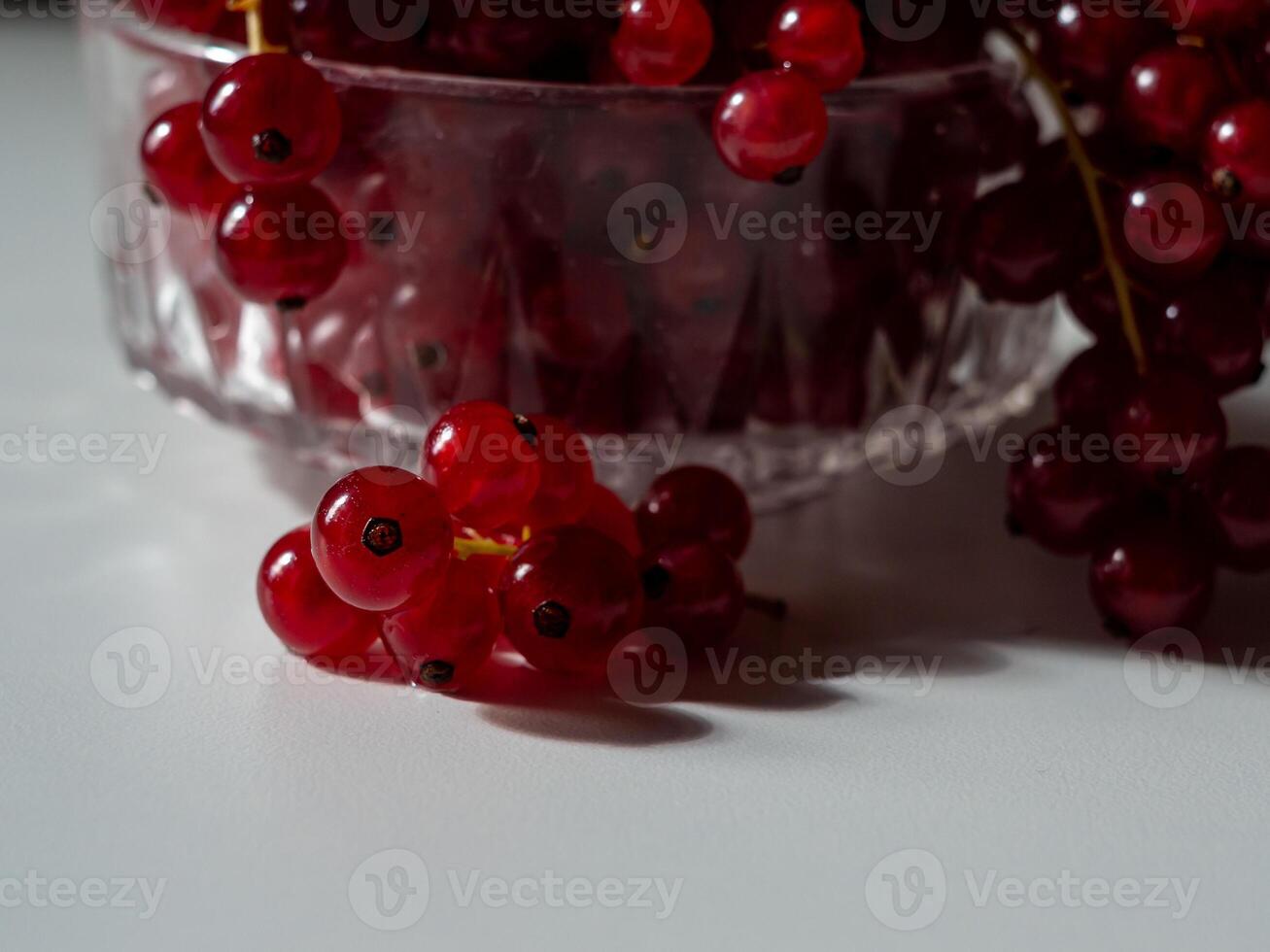 View of the bunches of red currants in a glass goblet on a black background photo