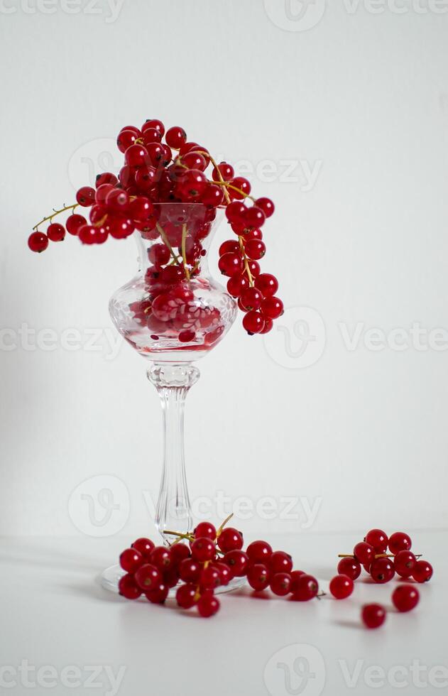 harvest of red currants in a crystal bowl on a white background photo