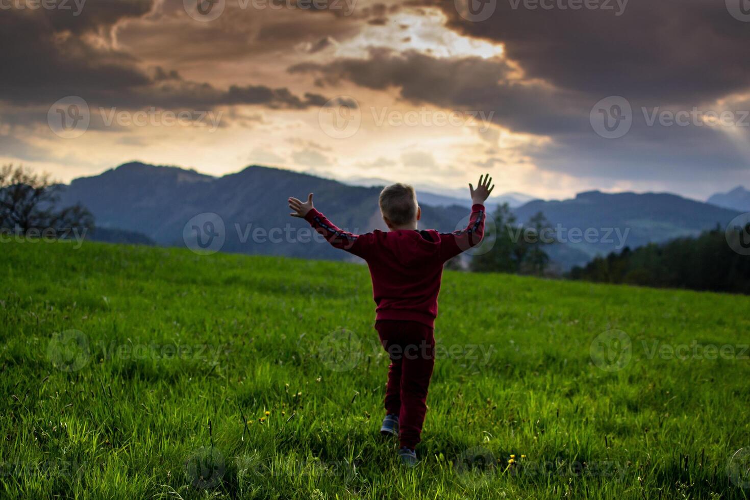 little boy runs in the rays of the sunset, hiking in the mountains photo