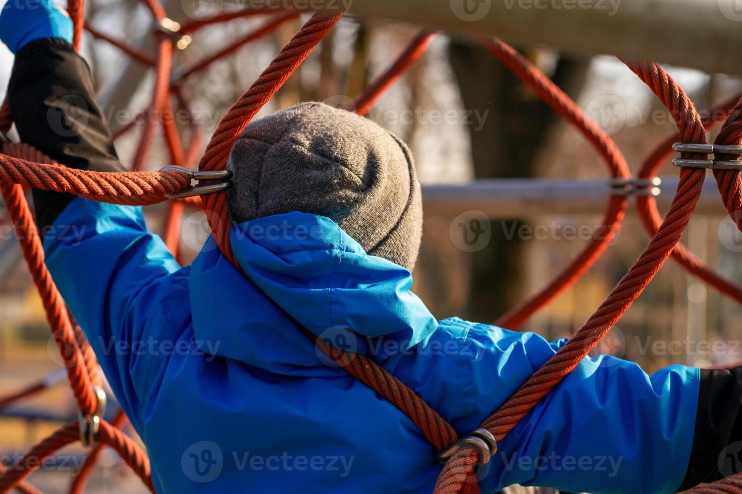 View of a boy in a blue jacket on the ropes at the playground photo