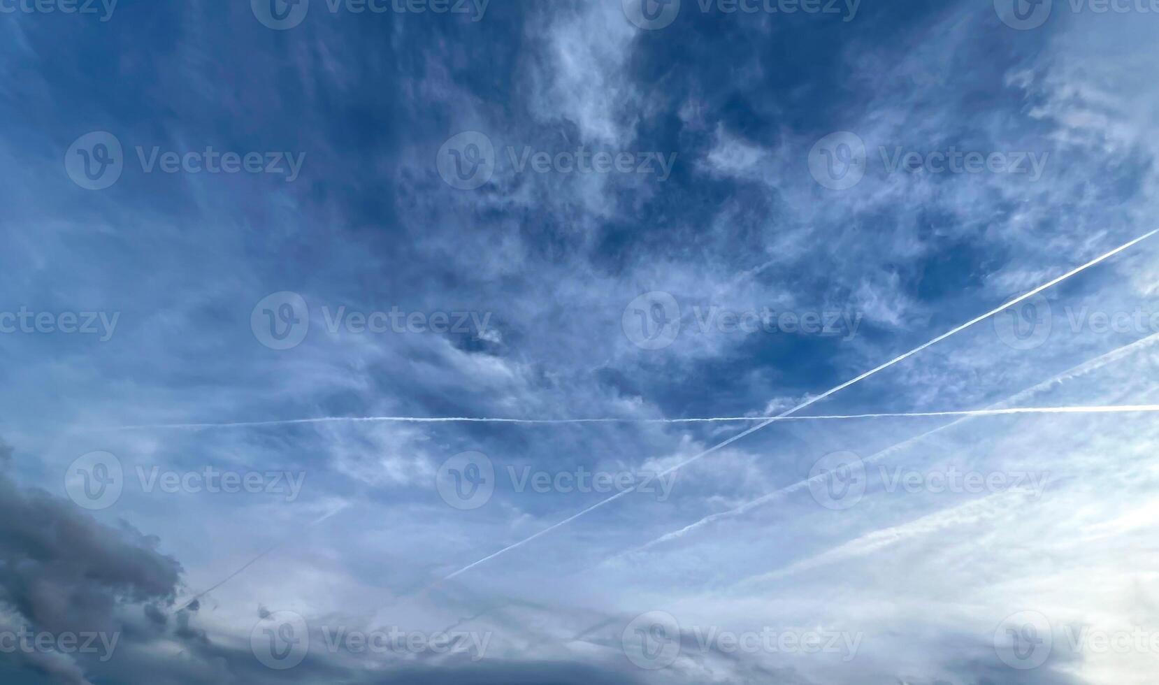 View of aircraft contrails and cloud clouds against blue sky photo