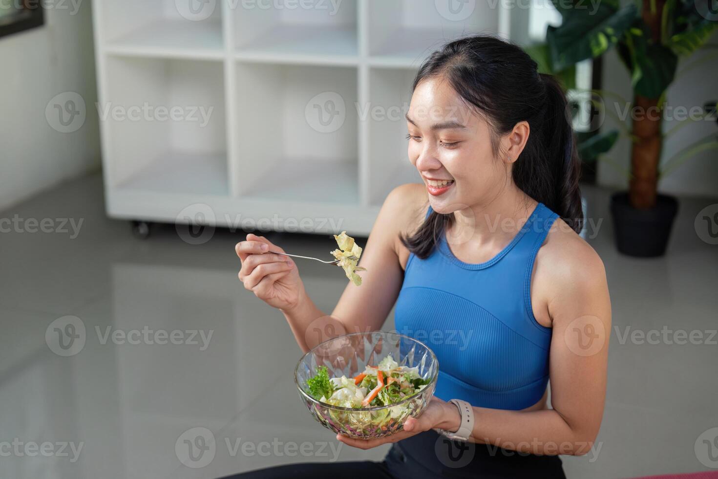 Joyful woman sitting on the floor and enjoying a healthy salad. photo