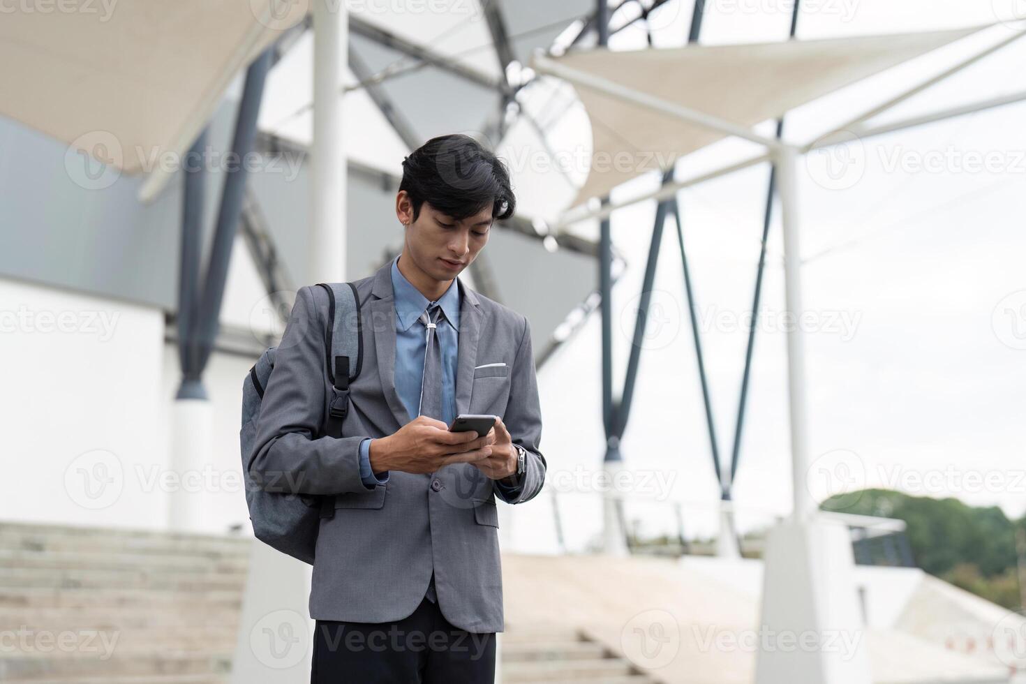 Young professional texting on smartphone outside a modern building, blending work and technology. photo