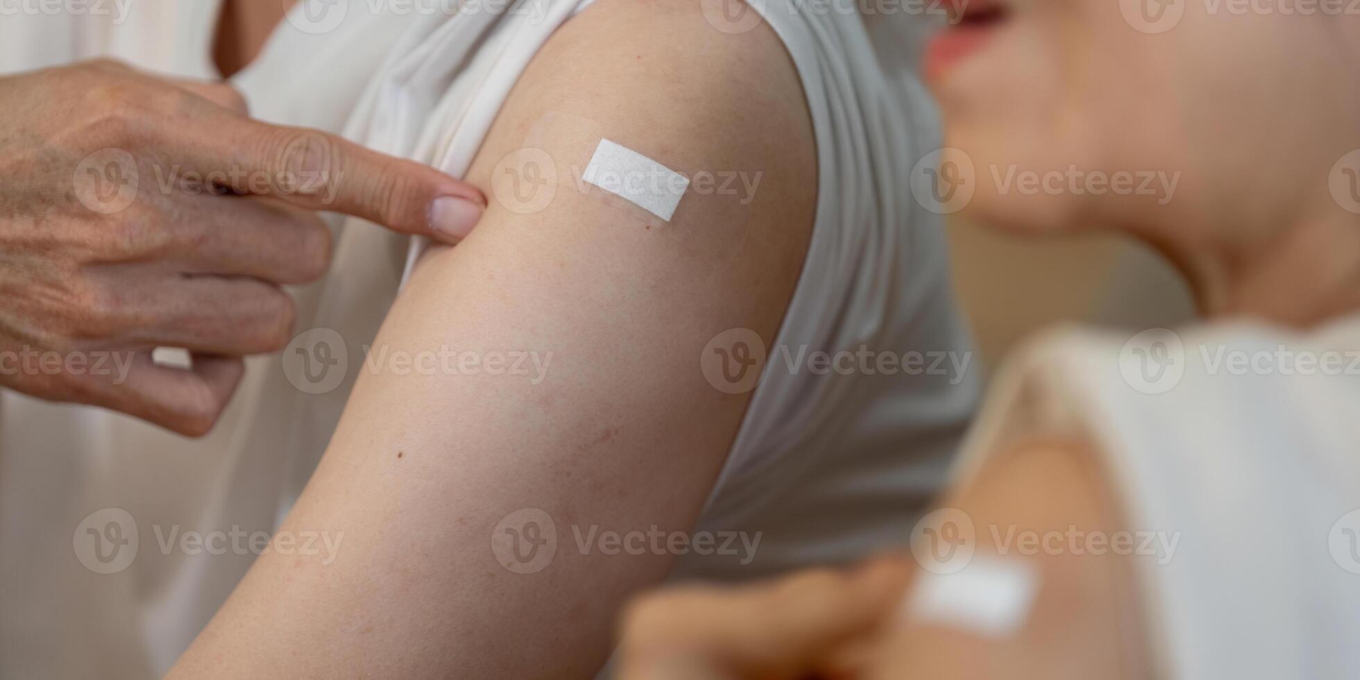 Elderly couple showing vaccination bandages, celebrating health and wellness after receiving shots. photo