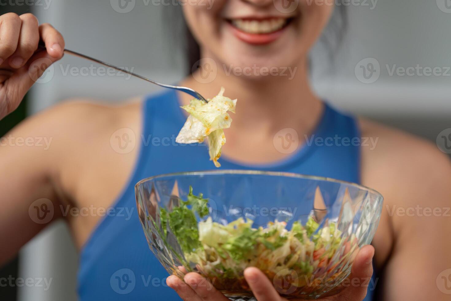 Close-up of a woman smiling while holding a forkful of salad, highlighting healthy eating. photo