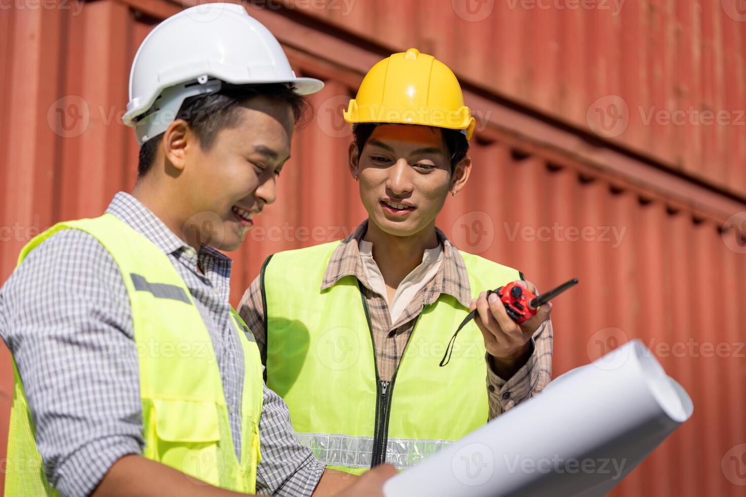 Engineers discussing logistics and construction plans with blueprints and a walkie-talkie. photo