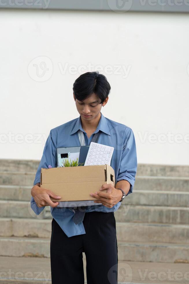 Young professional reflecting on career change while carrying a box of personal items from the office. photo