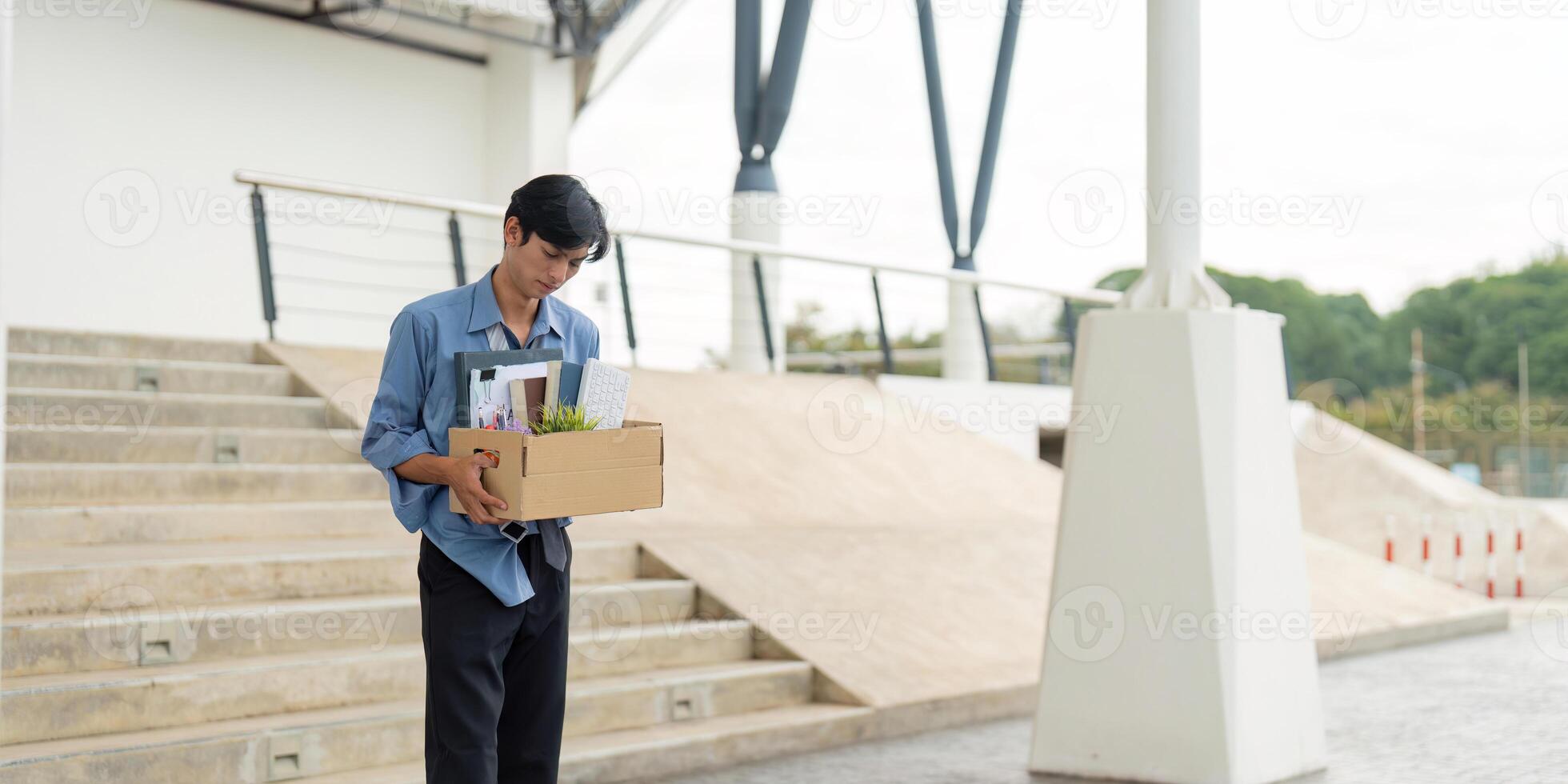 Man departing from workplace with a box of belongings, representing a significant career transition. photo