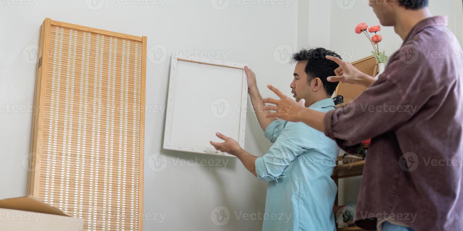 LGBTQ couple moving into a new home, discussing wall decor, and sharing ideas. photo