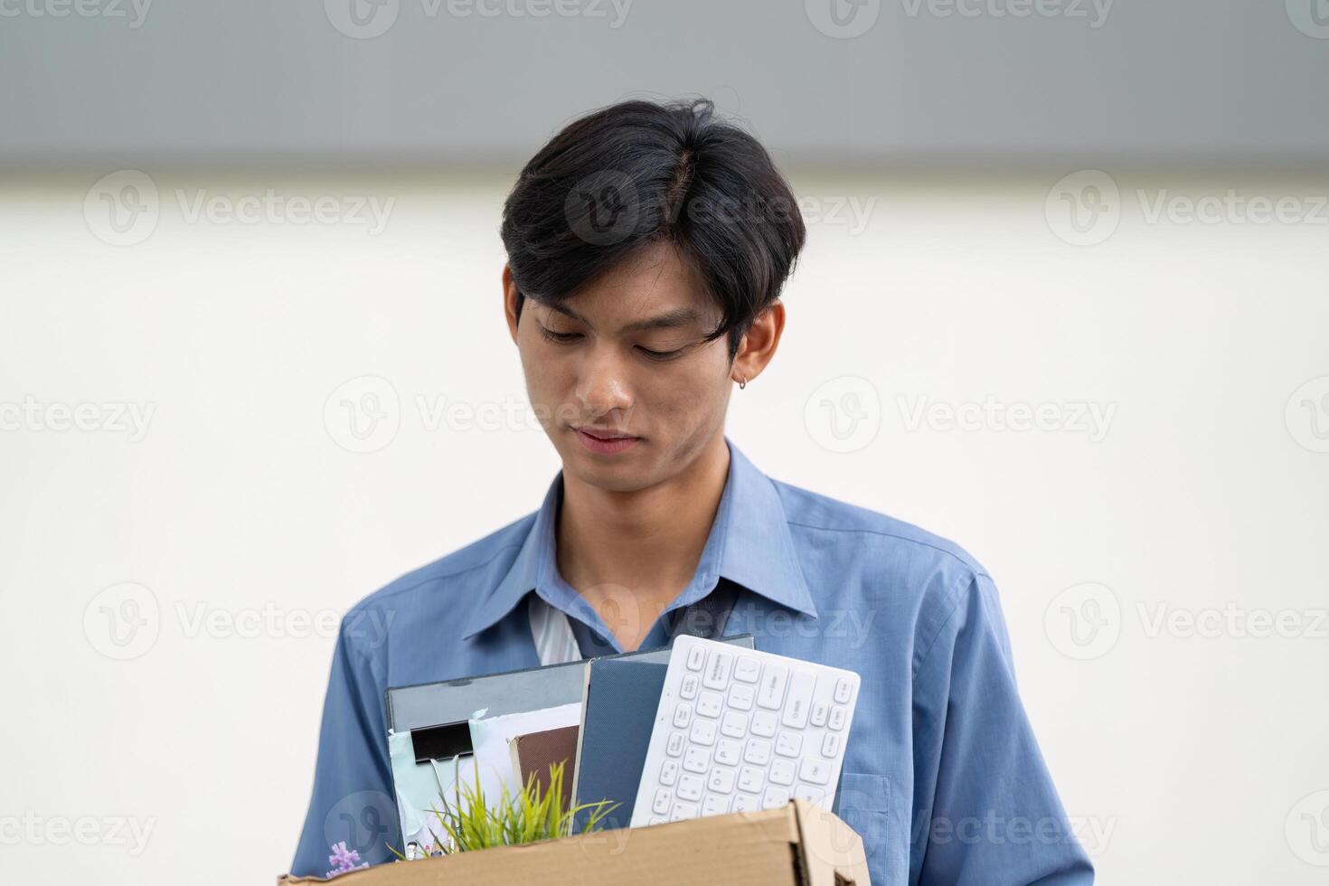Individual carrying a box of personal items, symbolizing the end of a job and the start of a new chapter. photo