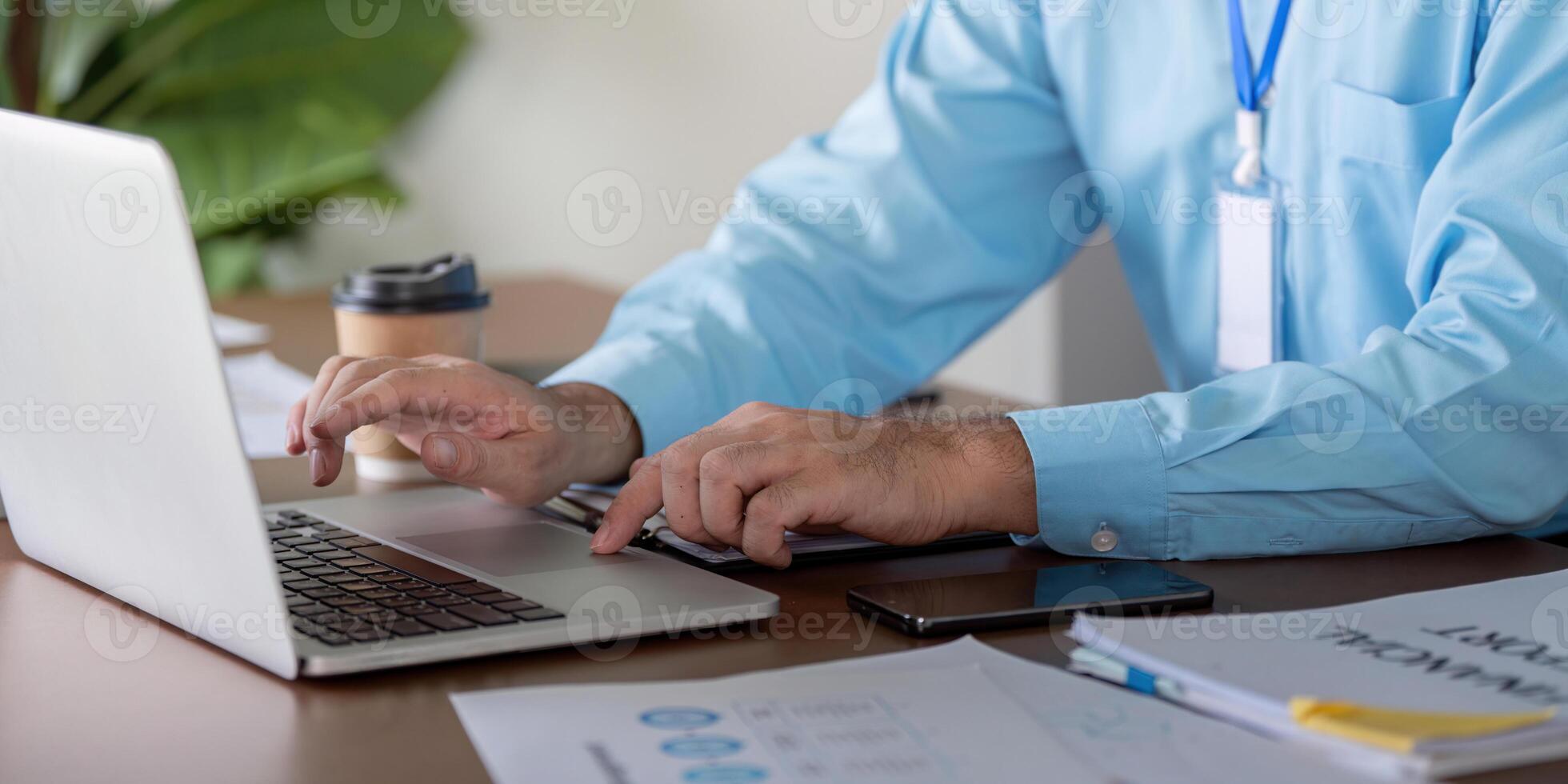Business professional typing on a laptop while managing finances and coffee in a modern workspace. photo