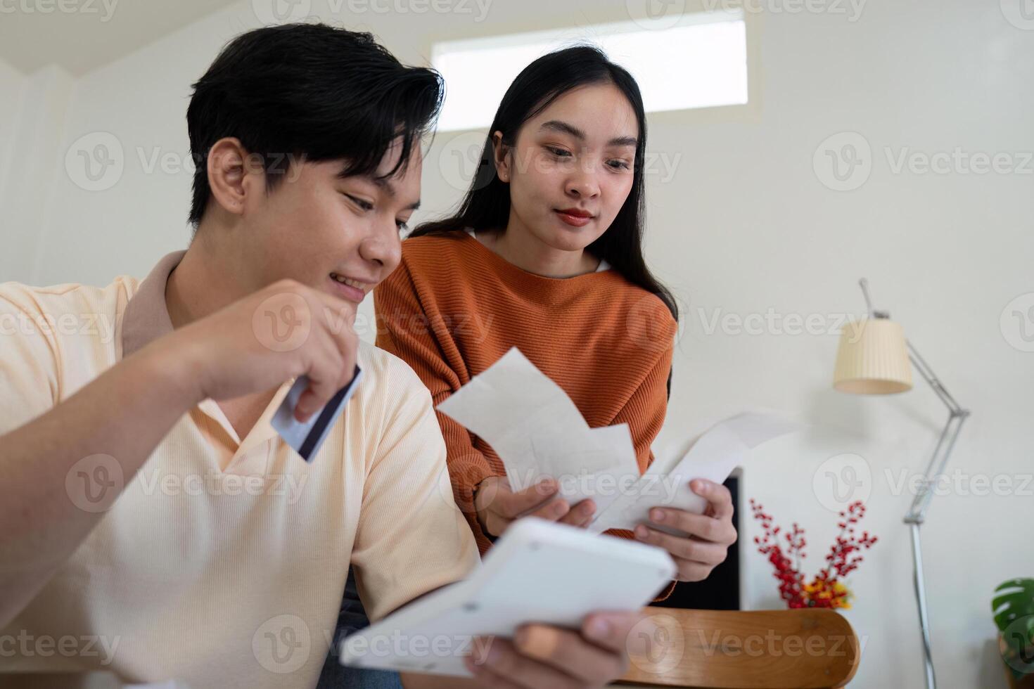 Couple managing bills and financial information with a credit card at home. photo