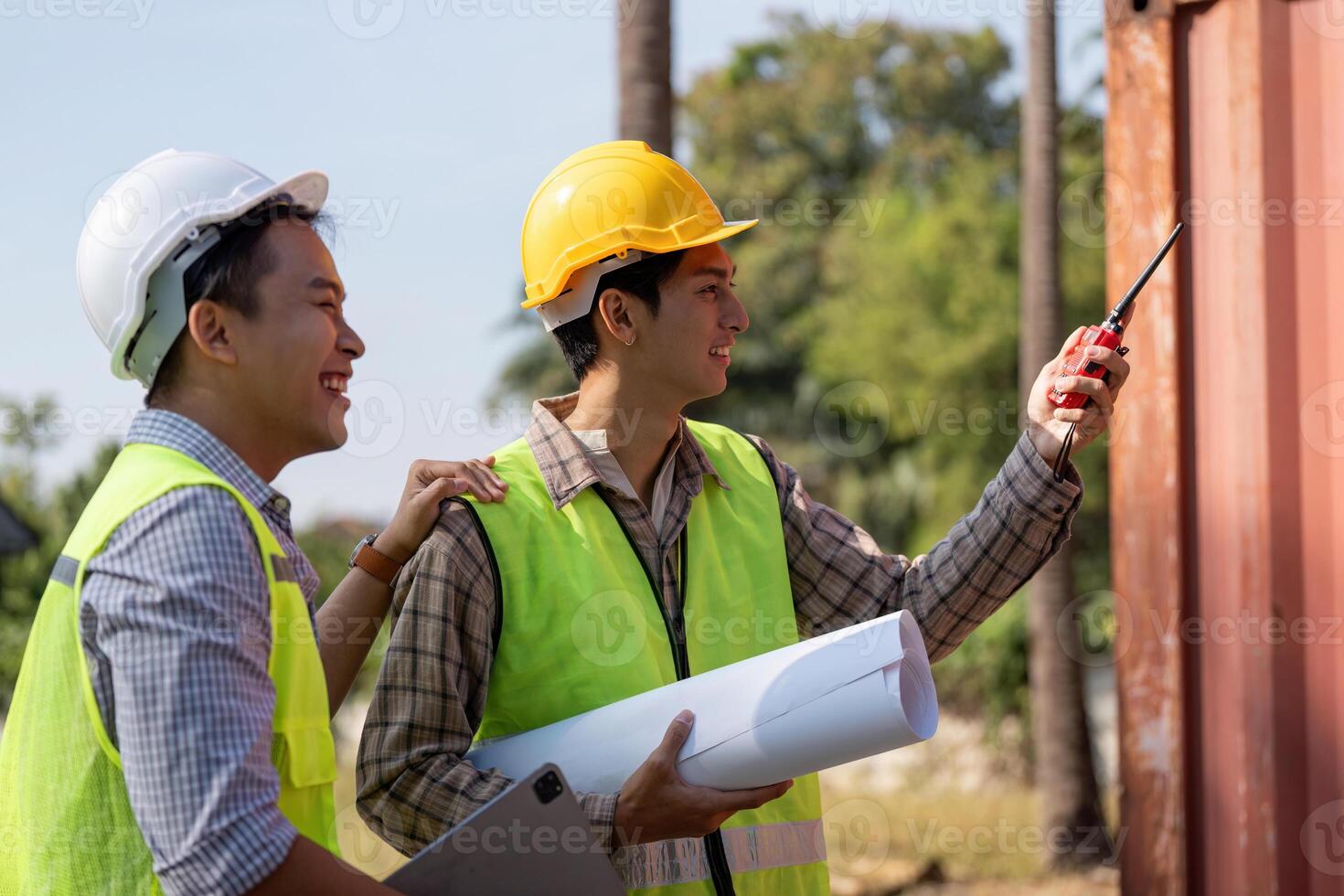 Engineers collaborating on construction plans outdoors with blueprints and communication devices. photo