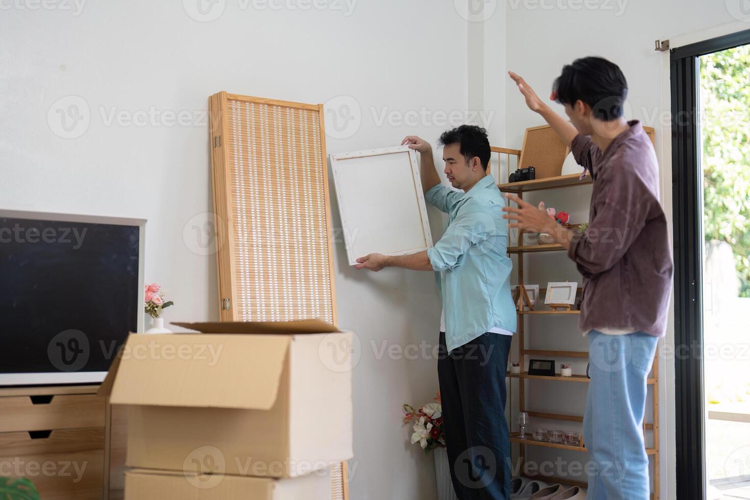 LGBTQ couple unpacking and arranging furniture in their new home, showcasing teamwork and love. photo