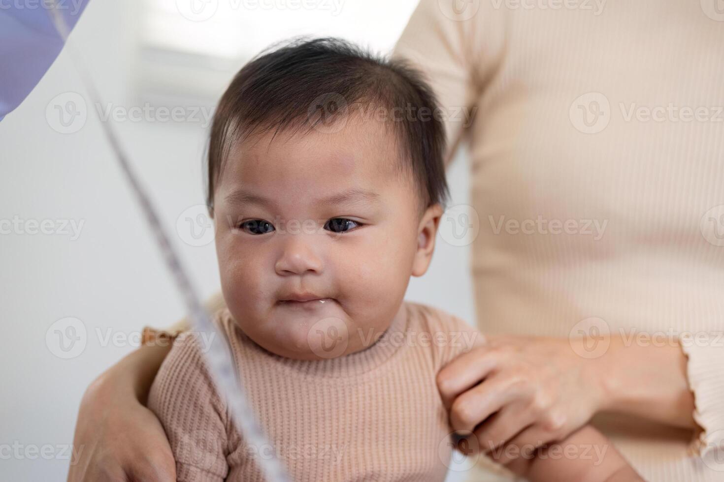 Pediatric doctor interacting with baby during a check up while parent supports child. photo