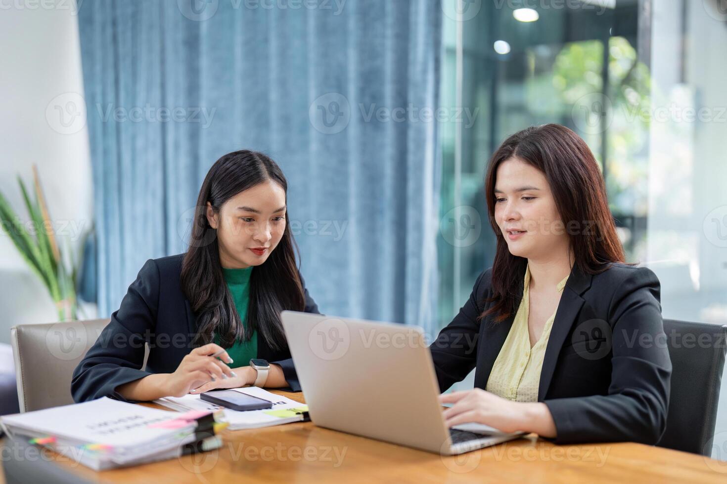 Professional women utilizing digital devices for project analysis and planning in a modern office environment. photo
