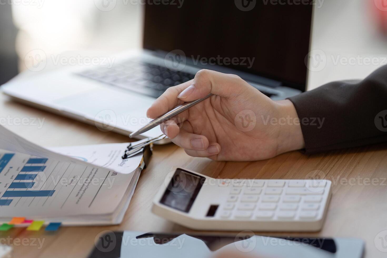 Business professional analyzing financial data and project plans with calculator and laptop in modern office. photo