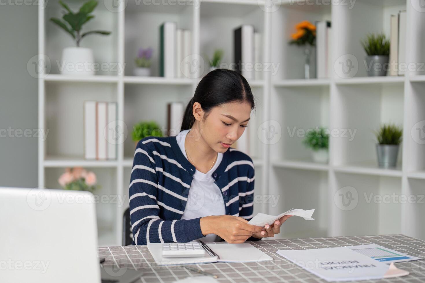 Young woman reviewing financial report and planning bills while seated at home. photo