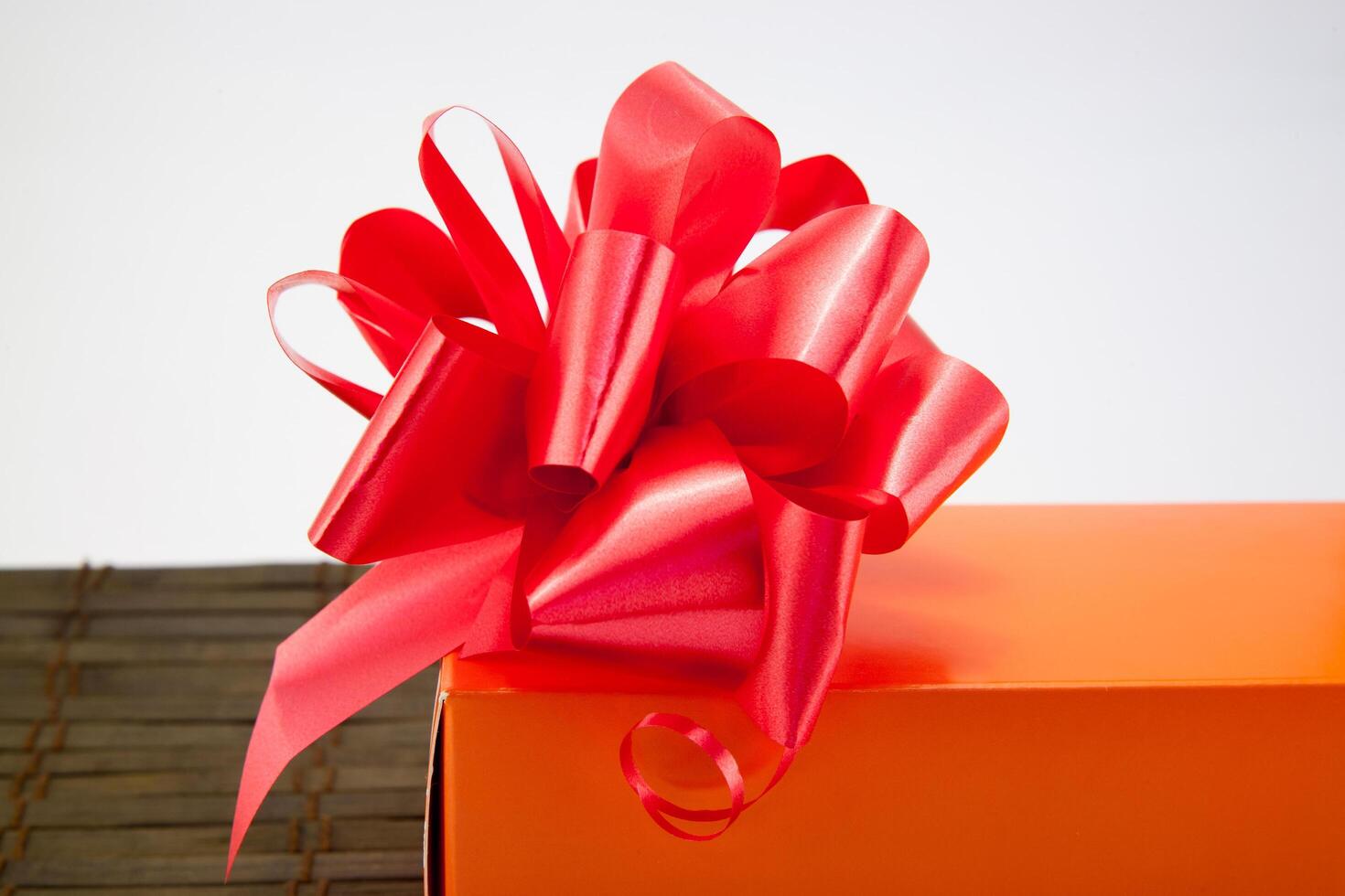 A red bow on an orange box with a bow photo