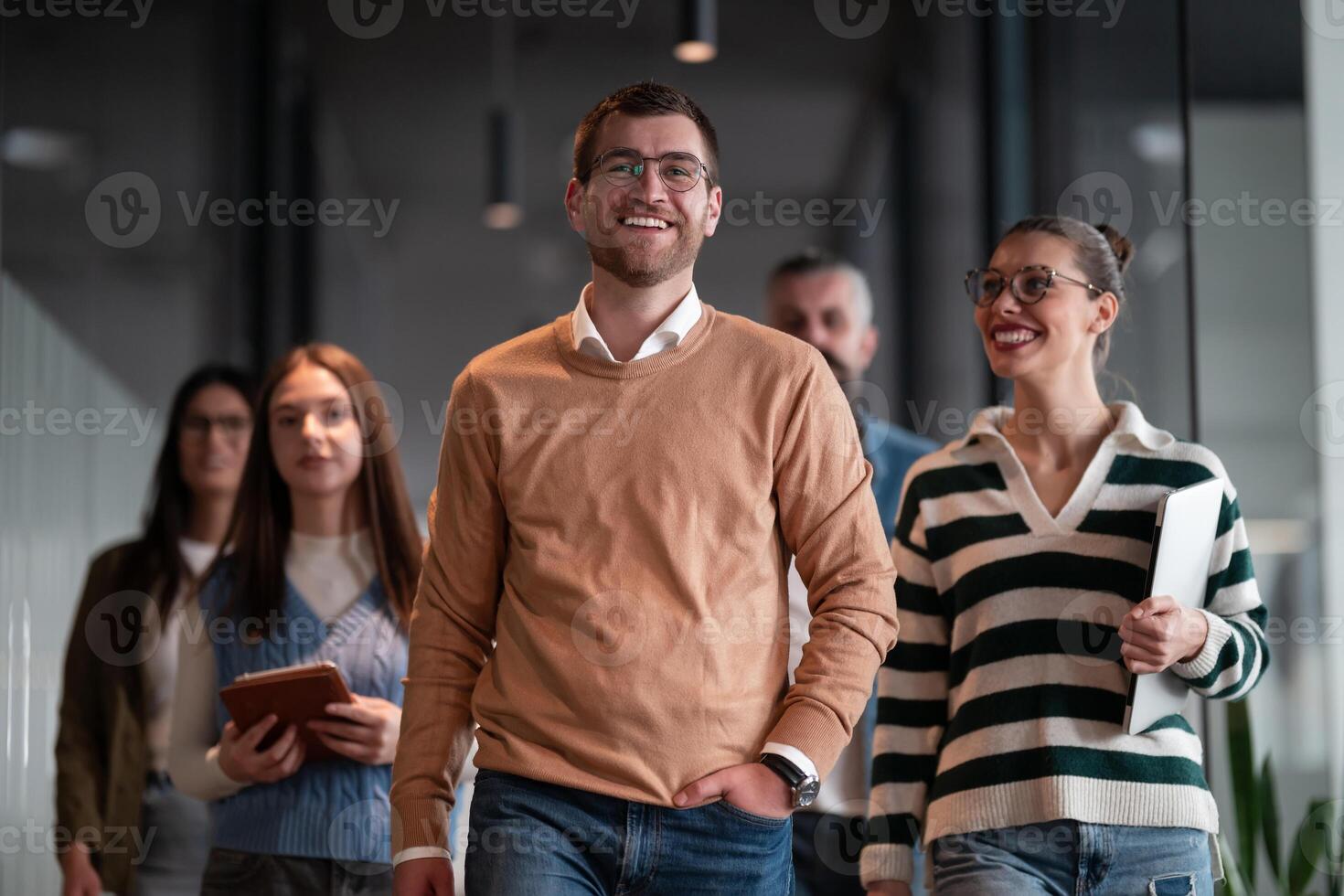 Business team in a modern open space startup office walking together. Diverse group of businesspeople smiling while having a discussion. Successful mixed race colleagues collaborating on a new project photo