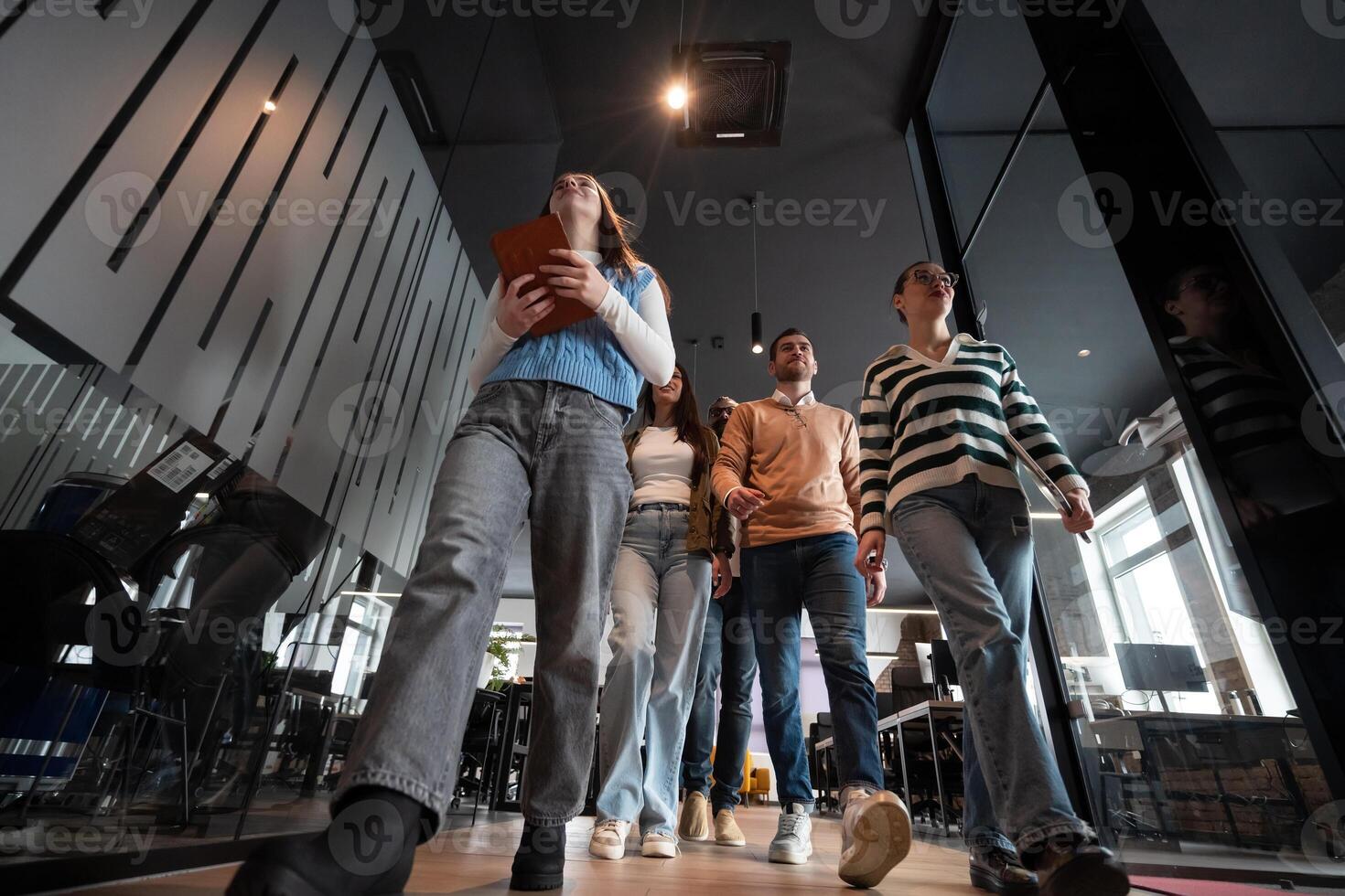 Business team in a modern open space startup office walking together. Diverse group of businesspeople smiling while having a discussion. Successful mixed race colleagues collaborating on a new project photo