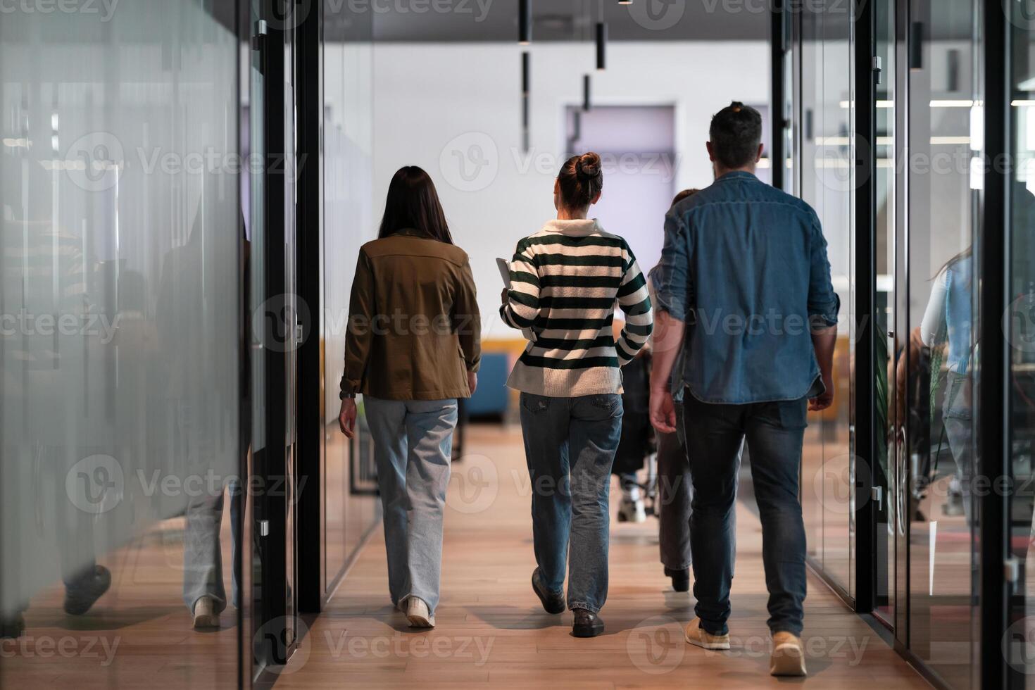 Business team in a modern open space startup office walking together. Diverse group of businesspeople smiling while having a discussion. Successful mixed race colleagues collaborating on a new project photo