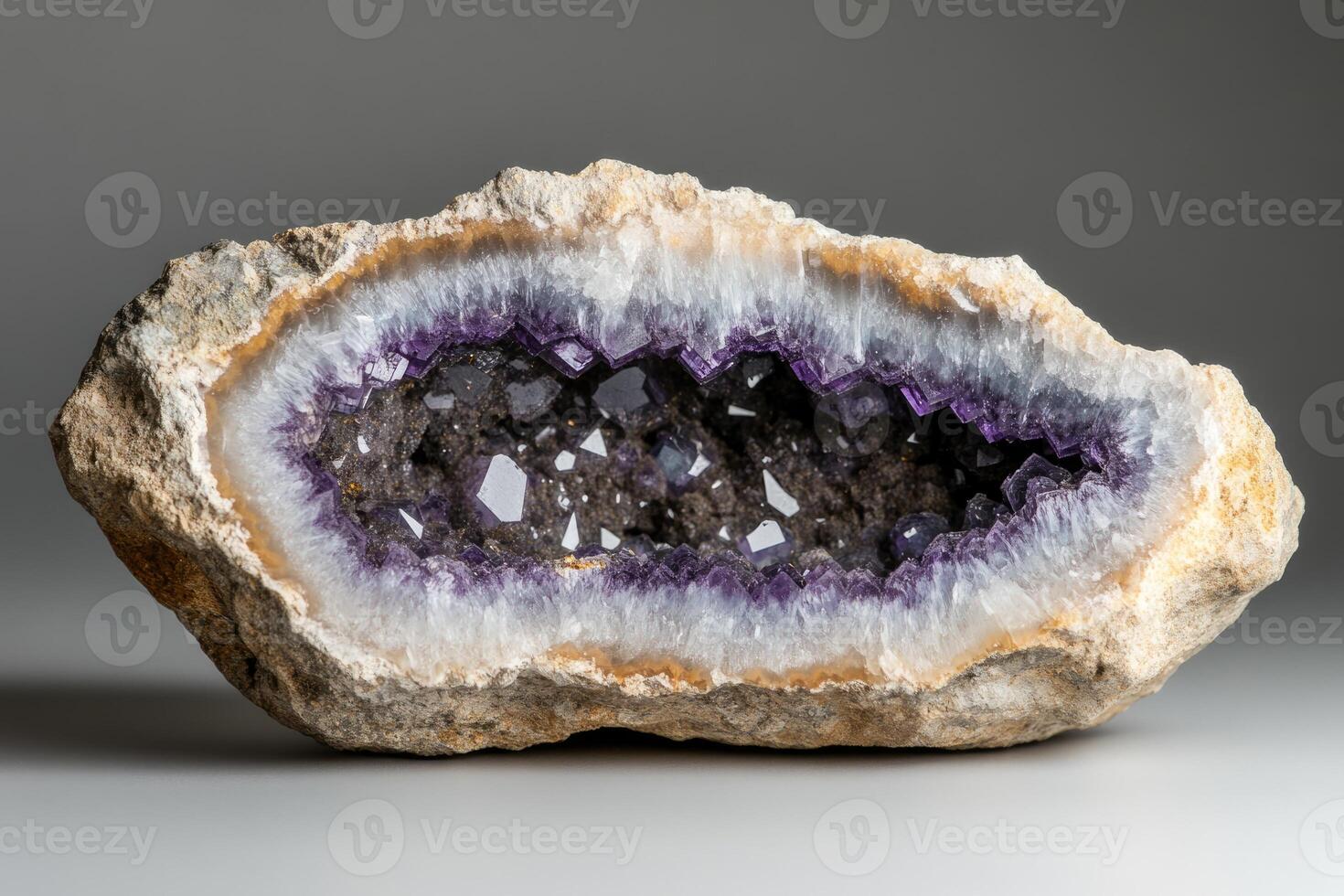 The stunning amethyst geode features a rough exterior with a vibrant interior filled with sparkling purple crystals, creating a captivating visual effect in subtle lighting photo